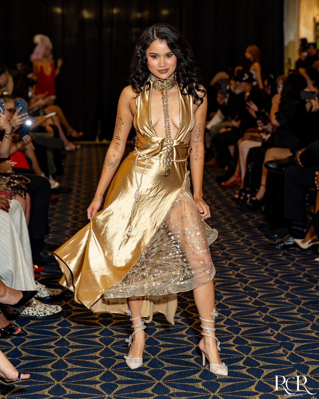 Model in a gold dress walking past Gatsby Affair guests