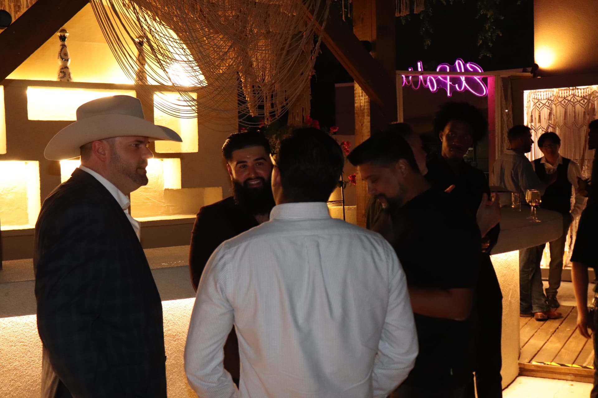 Guests talking with a cowboy-hatted attendee on the Old Money terrace