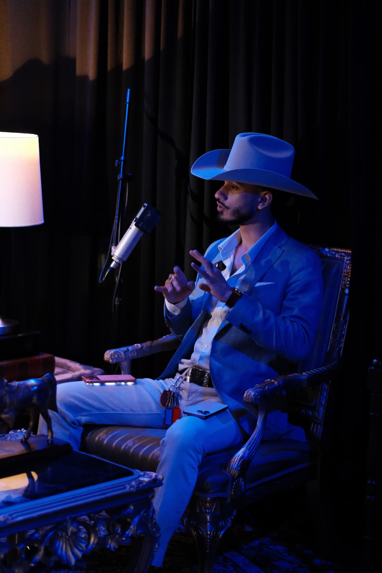 Cowboy-hatted HLE host seated at a microphone under blue studio lighting